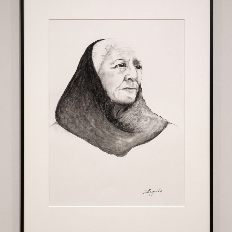 A framed monochrome portrait drawing displayed on a wall.