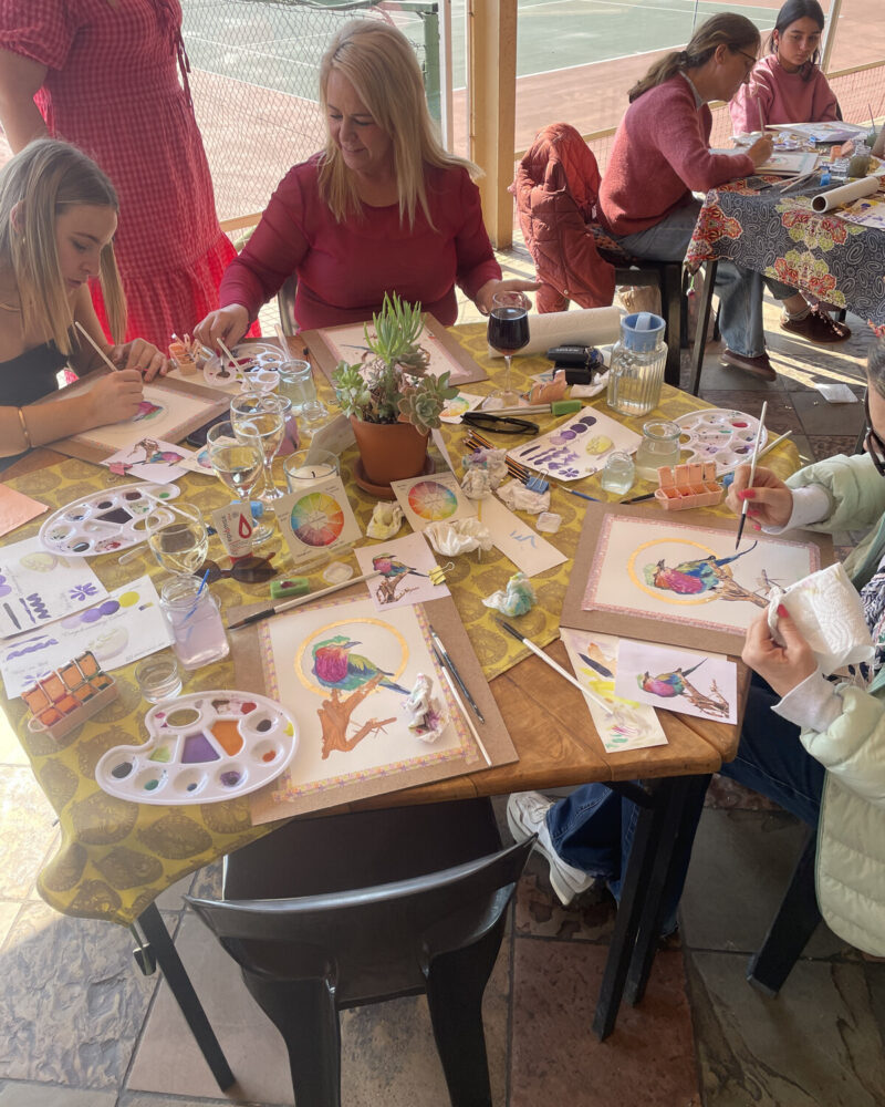A private workshop table with paints and paper mid-session.