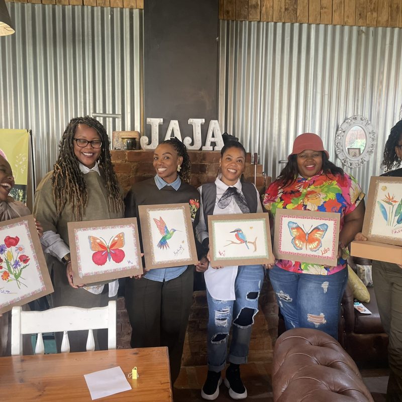 Workshop participants holding up their finished watercolour paintings.