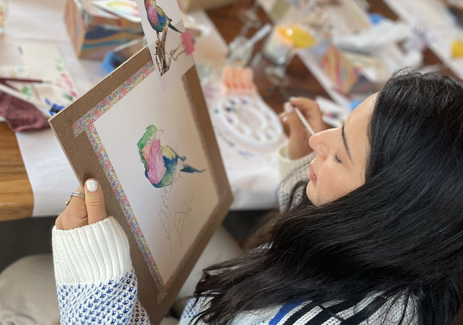 A participant painting a watercolour bird at a workshop table.