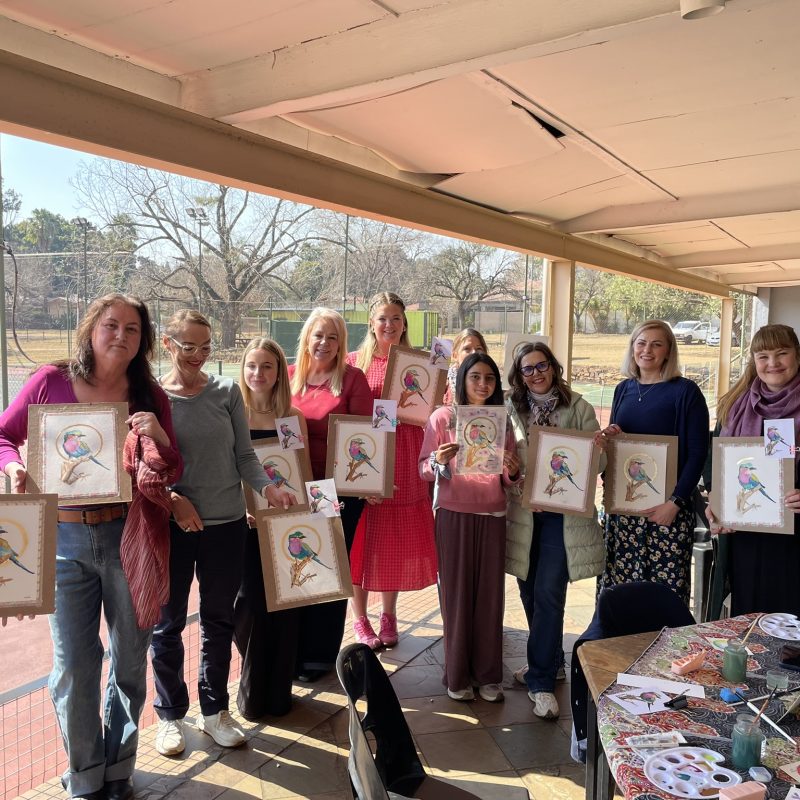 A workshop group holding up their finished framed watercolours.