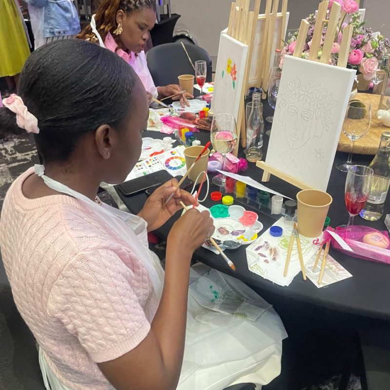A participant painting at a table set with small easels and canvases.