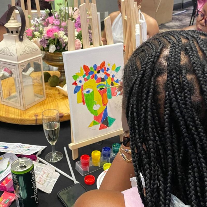 A participant with her colourful portrait painting at a paint-and-sip table.